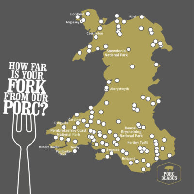 A stylized map of Wales with various locations marking the locations of Porc Blasus suppliers, accompanied by a large fork and the text “HOW FAR IS YOUR FORK FROM OUR PORC?” at the bottom. The map features cities like Swansea, natural parks like Snowdonia National Park, and towns such as Holyhead and Aberystwyth. 